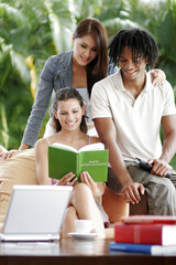 Two ladies and an African American man sharing a book