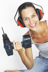 A woman with headphone lifting up a driller like lifting up a dumbbell