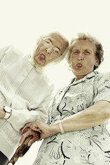 Low angle view of two old women showing their tongues at the camera