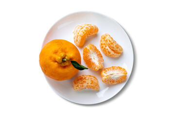 Whole Ponkan tangerine and one peeled in segments on a plate isolated on white background. Top view