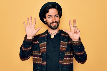 Young handsome hispanic bohemian man wearing hippie style and boho hat showing and pointing up with fingers number eight while smiling confident and happy.