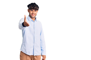 Young hispanic man wearing casual shirt smiling friendly offering handshake as greeting and welcoming. successful business.