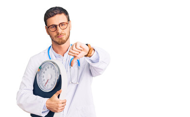 Handsome young man with bear as nutritionist doctor holding weighing machine with angry face,...