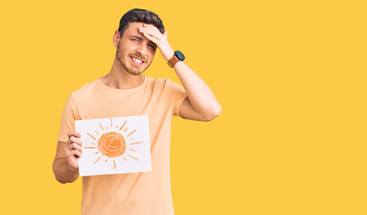 Handsome young man with bear holding sun draw stressed and frustrated with hand on head, surprised...