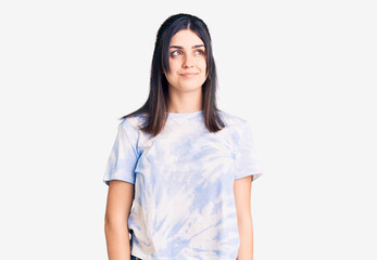 Fototapeta premium Młoda piękna dziewczyna ubrana dorywczo t shirt, uśmiechając się, patrząc z boku i patrząc od myślenia.