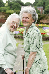 Two old women with walking sticks walking in the park