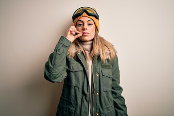 Young brunette skier woman wearing snow clothes and ski goggles over white background mouth and...