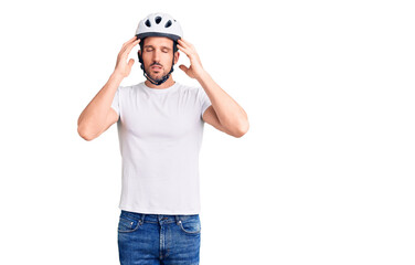 Young handsome man wearing bike helmet with hand on head for pain in head because stress. suffering migraine.
