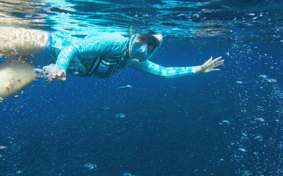 Young woman in snorkeling mask underwater photo. Snorkel in oxygen bubbles undersea. Snorkeling in tropical sea.