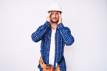 Young handsome man weaing handyman uniform suffering from headache desperate and stressed because pain and migraine. hands on head.