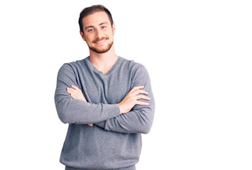 Young handsome caucasian man wearing casual winter sweater happy face smiling with crossed arms looking at the camera. positive person.