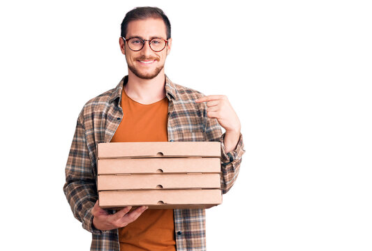 Young handsome caucasian man holding delivery pizza box pointing finger to one self smiling happy and proud