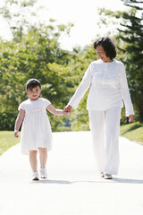 Fototapeta premium An old lady and her granddaughter walking together holding hands in the park