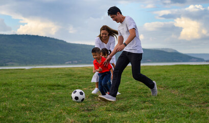 Cheerful family Asian playing football in a green lawn