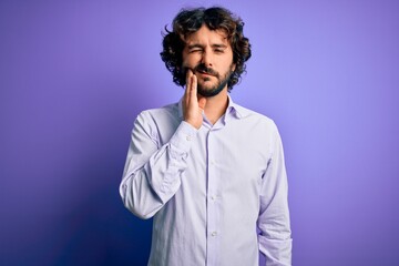 Young handsome business man with beard wearing shirt standing over purple background touching mouth with hand with painful expression because of toothache or dental illness on teeth. Dentist