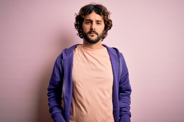 Young handsome sporty man with beard wearing casual sweatshirt over pink background Relaxed with serious expression on face. Simple and natural looking at the camera.