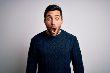 Obraz premium Young handsome man with beard wearing casual sweater standing over white background afraid and shocked with surprise expression, fear and excited face.