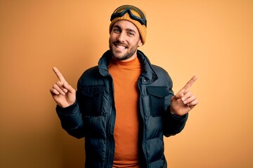 Young handsome skier man with beard wearing snow sportswear and ski goggles smiling confident pointing with fingers to different directions. Copy space for advertisement