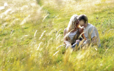 Naklejka na ściany i meble A couple sitting on the grass kissing