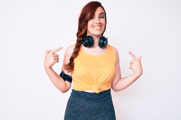 Young beautiful woman wearing gym clothes and using headphones looking confident with smile on...