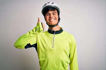 Young handsome cyclist man wearing security bike helmet over isolated white background doing happy thumbs up gesture with hand. Approving expression looking at the camera showing success.