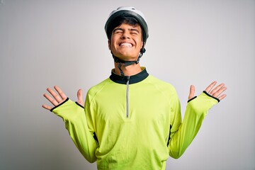 Young handsome cyclist man wearing security bike helmet over isolated white background celebrating mad and crazy for success with arms raised and closed eyes screaming excited. Winner concept
