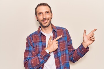 Young handsome man wearing casual clothes smiling and looking at the camera pointing with two hands and fingers to the side.