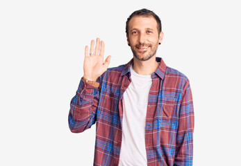 Young handsome man wearing casual clothes waiving saying hello happy and smiling, friendly welcome gesture