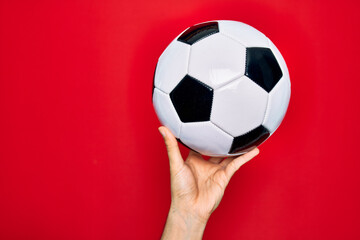 Beautiful hand of man holding football ball over isolated red background