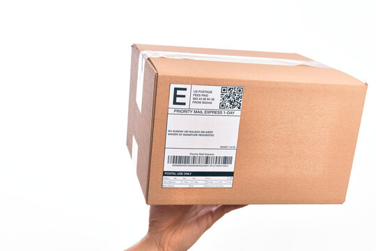 Hand of caucasian young man holding cardboard package showing label with codebar over isolated white background