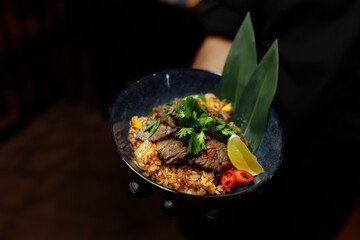 Fried rice with beef and vegetables in a waiter's hand with a glove