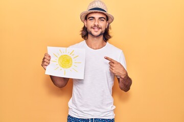 Young handsome man holding sun draw smiling happy pointing with hand and finger
