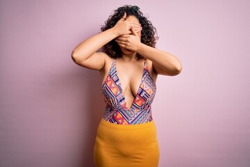 Young beautiful arab woman on vacation wearing swimsuit and sunglasses over pink background Covering eyes and mouth with hands, surprised and shocked. Hiding emotion