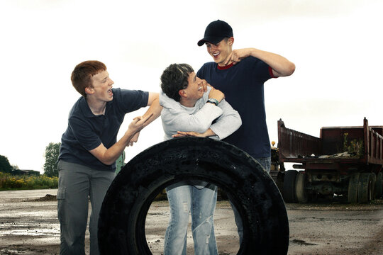 Three boys posing with a big tyre