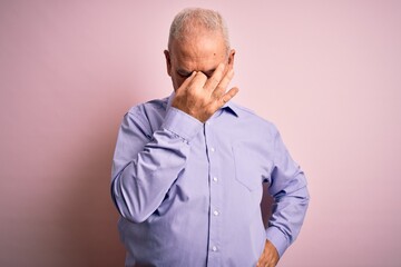 Fototapeta premium Middle age handsome hoary man wearing casual shirt standing over pink background tired rubbing nose and eyes feeling fatigue and headache. Stress and frustration concept.