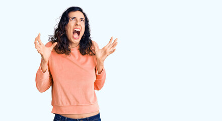 Obraz premium Young beautiful hispanic woman wearing casual clothes crazy and mad shouting and yelling with aggressive expression and arms raised. frustration concept.