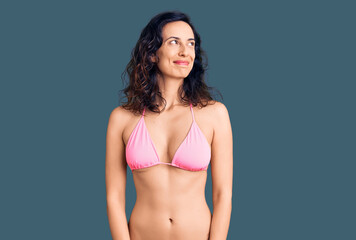 Young beautiful hispanic woman wearing bikini smiling looking to the side and staring away thinking.