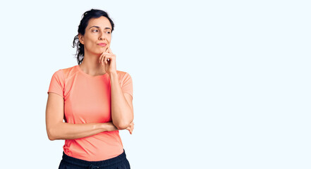 Young beautiful hispanic woman wearing sportswear serious face thinking about question with hand on...