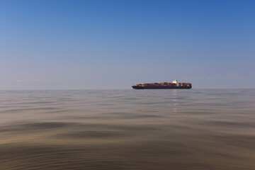 Cargo ship on the morning sea in a clear day and clear sky.