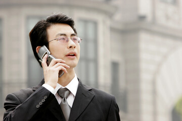 A bespectacled businessman talking on the hand phone