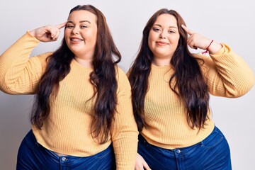 Young plus size twins wearing casual clothes smiling pointing to head with one finger, great idea or thought, good memory