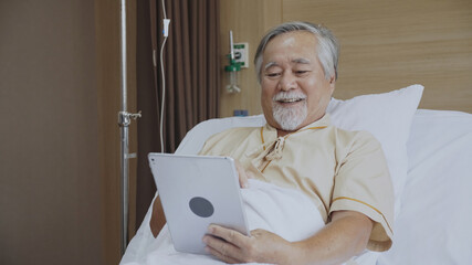 Concept tele health. Elderly Asian man using tablet and talk to family In the hospital. Patient in video conferencing with general practitioner on digital tablet. Sick man in online consultation.