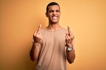 Young handsome african american man wearing casual t-shirt standing over yellow background Showing...