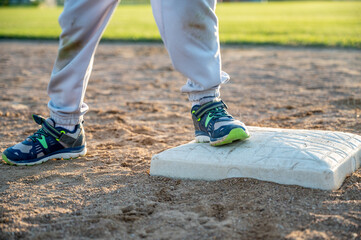 Youth baseball with a runner safe on base with a left foot tagged