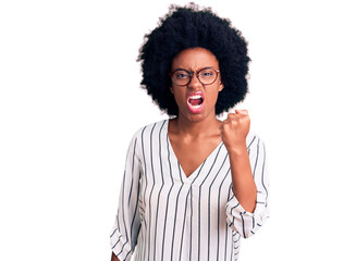 Young african american woman wearing casual clothes and glasses angry and mad raising fist frustrated and furious while shouting with anger. rage and aggressive concept.