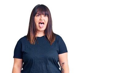 Fototapeta premium Young plus size woman wearing casual clothes sticking tongue out happy with funny expression. emotion concept.