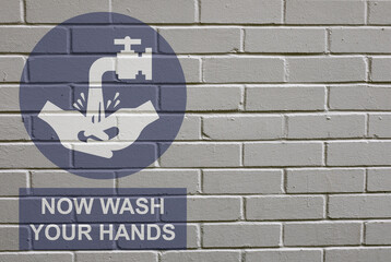 Obraz premium White decayed faded brick wall background with now wash your hands message sign to stop the spread of the worldwide pandemic