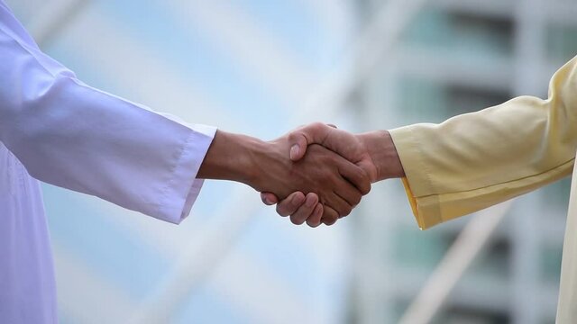 Arab Businessman shaking hands together. Teamwork business partner wear Muslim dress Shake Hands with Partnership Concept. Success UAE diversity people trust make commitment by handshake