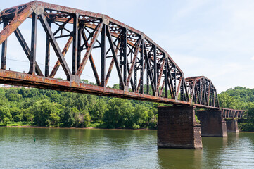 An old steel railroad trestle bridge over the Monongahela River in Homestead, Pennsylvania, USA on a sunny summer day