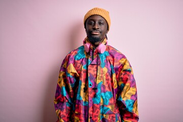 Young handsome african american man wearing colorful coat and cap over pink background depressed and worry for distress, crying angry and afraid. Sad expression.